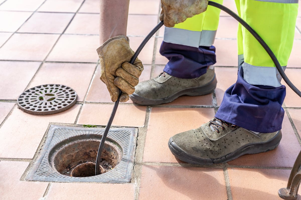High-pressure water jet clearing a blocked yard drain